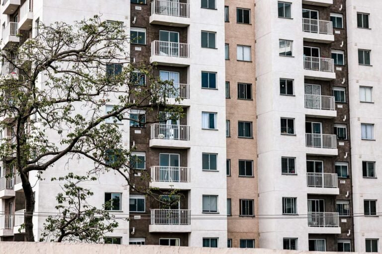 Exterior view of a modern apartment building with balconies and a tree, showcasing urban a