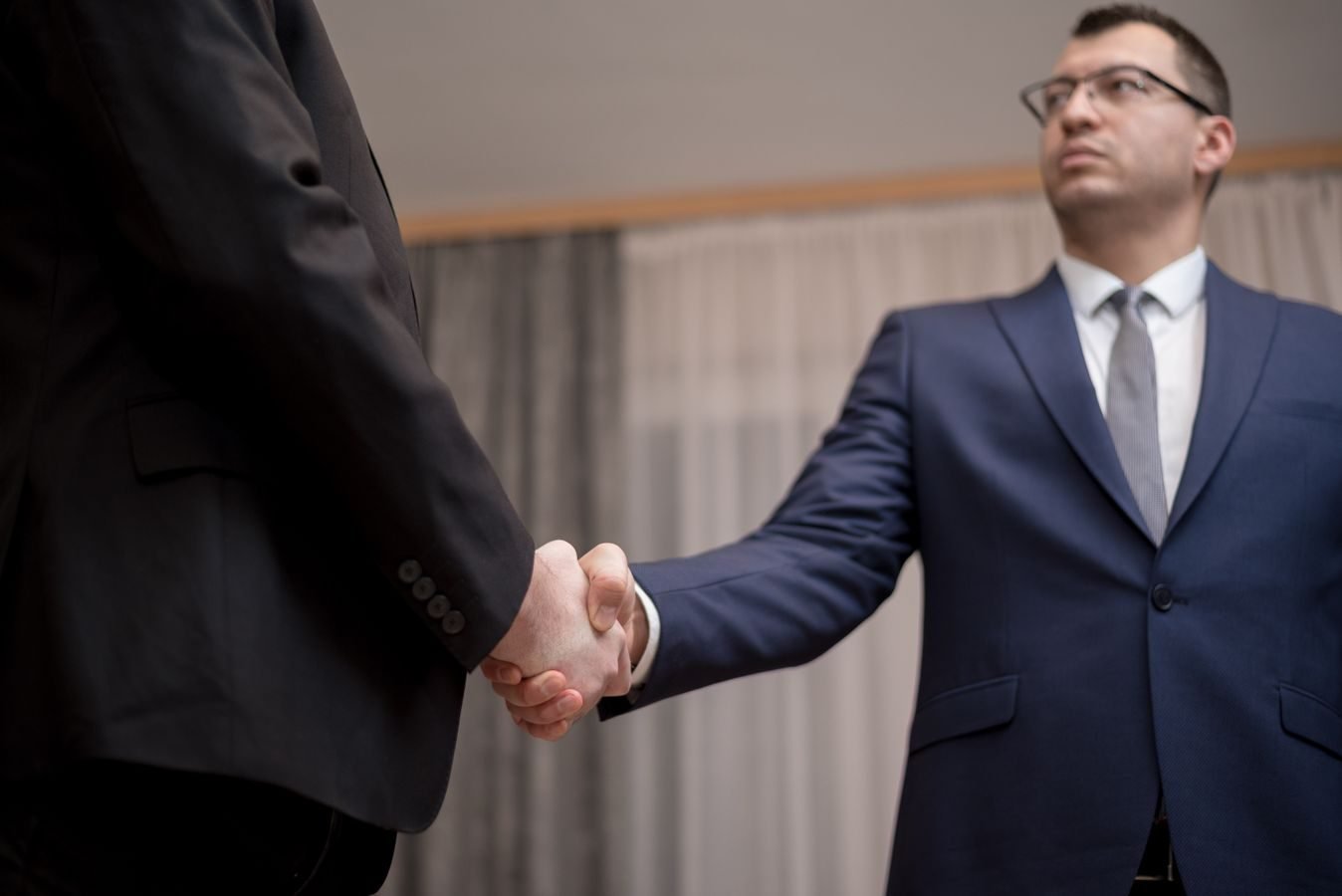 Two businessmen in formal attire shaking hands during a meeting.