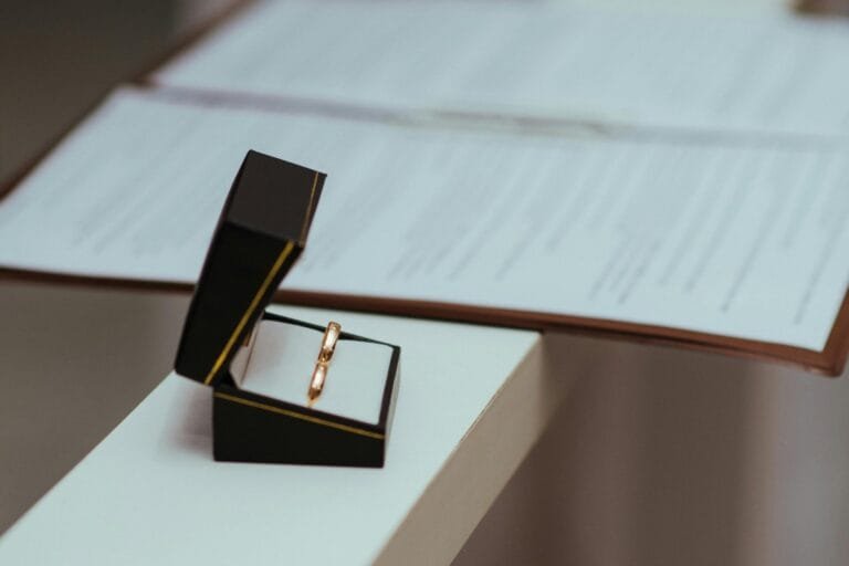 Divórcio Litigioso: Procedimento, Prazos e Direitos das Partes 6 A pair of wedding rings in a black box next to important documents, symbolizing commitment.