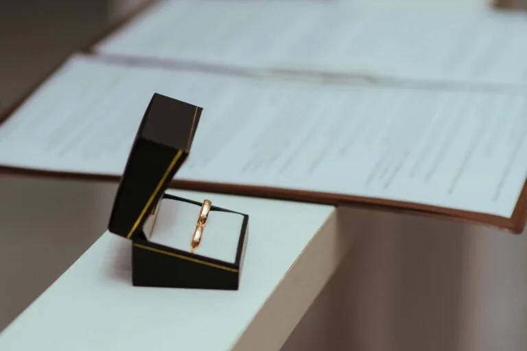 A pair of wedding rings in a black box next to important documents, symbolizing commitment.