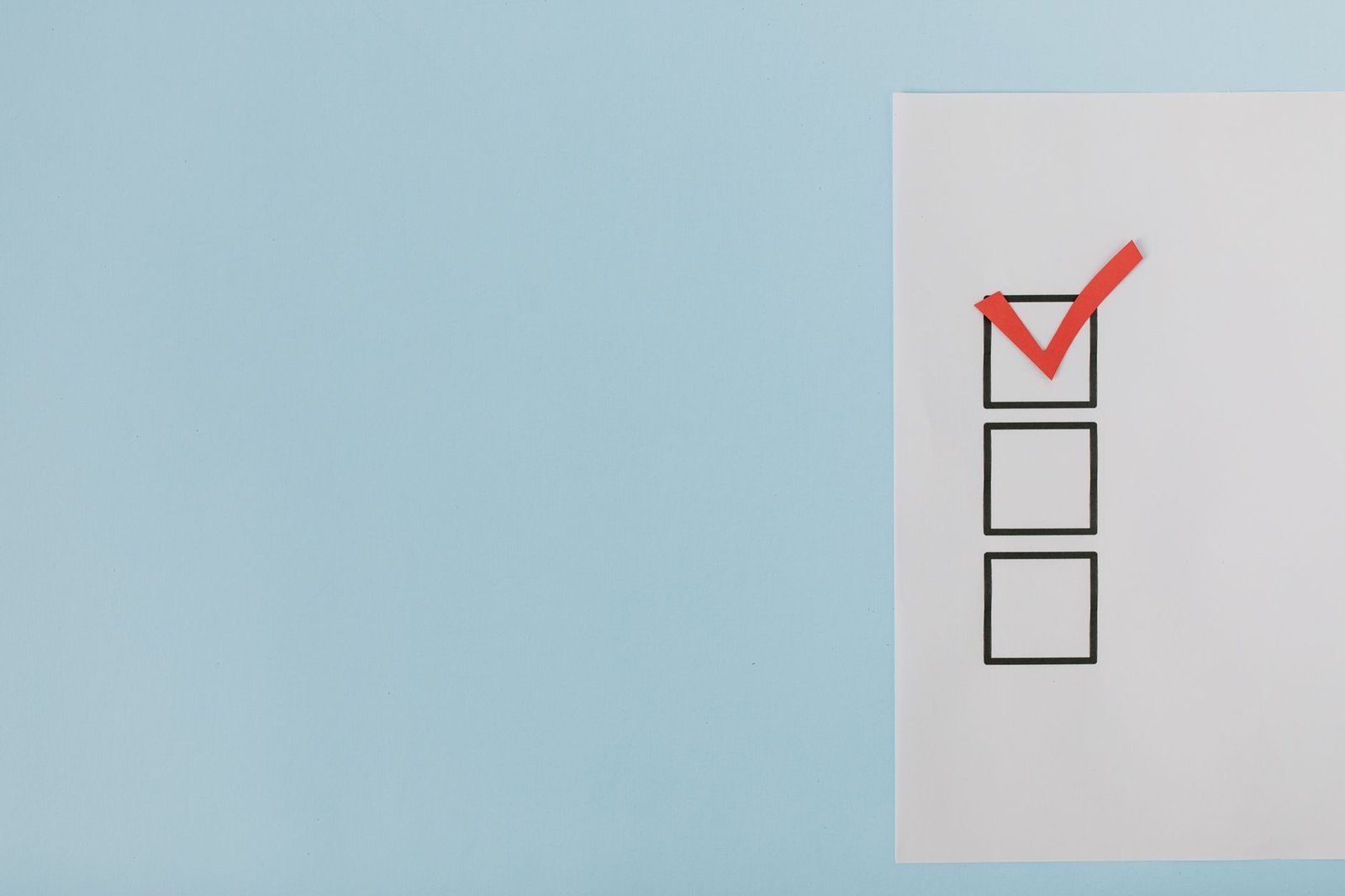 A minimalist checklist with a red checkmark on a blue background, providing ample copy spa