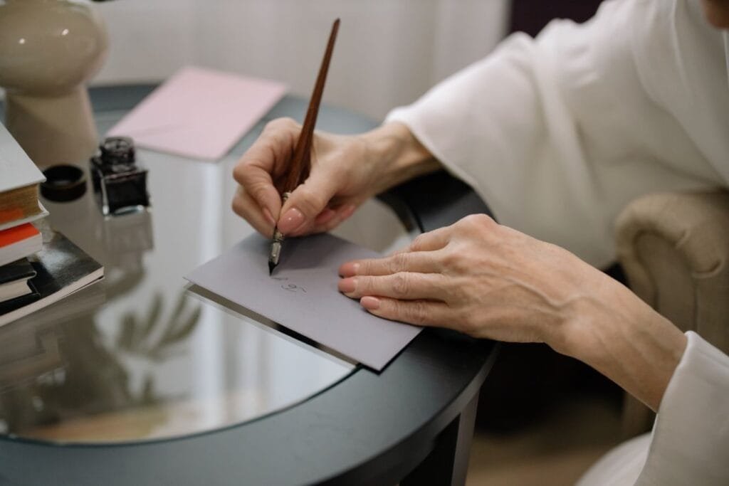 Quais documentos preciso reunir para pedir minha aposentadoria? 1 Close-up of hands elegantly writing on a gray envelope using a fountain pen.