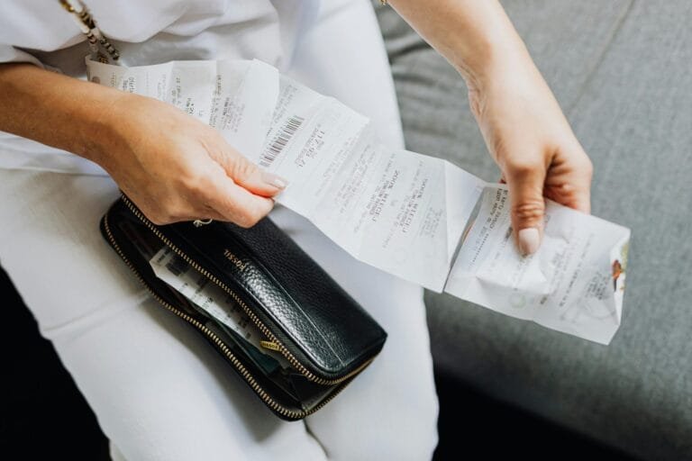 Close-up of a womans hands managing multiple receipts taken from a black wallet.