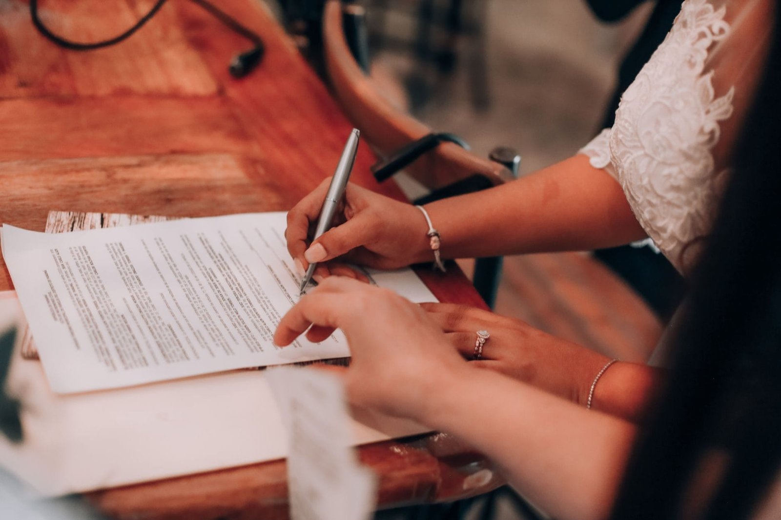 Hands signing an important document at a wooden table, symbolizing agreement and commitmen
