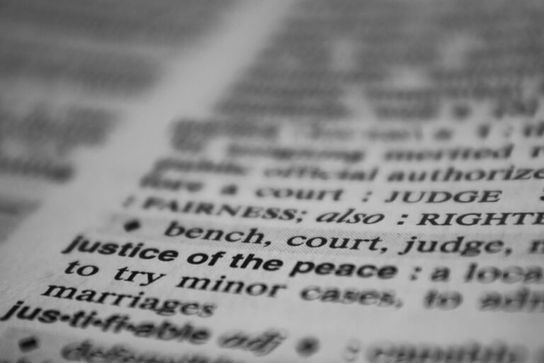 Selective focus on the word justice in a dictionary, conveying law and fairness concepts.