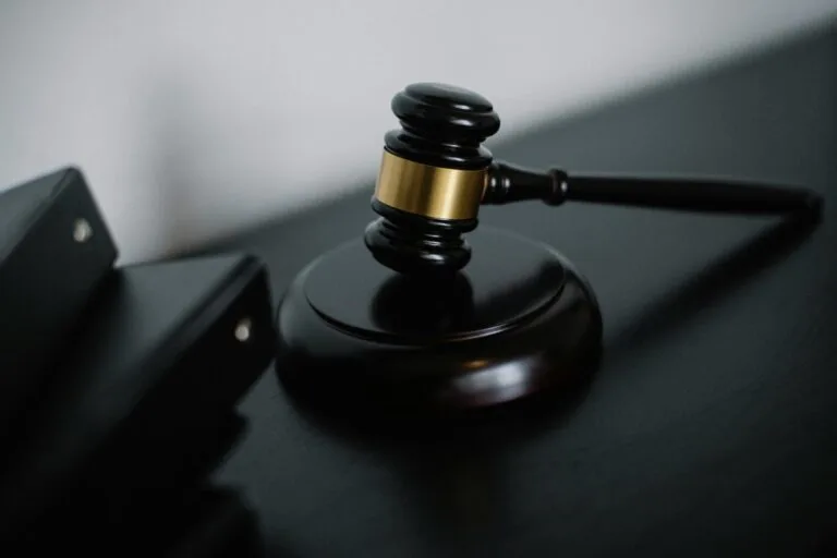 High angle of shiny wooden ceremonial mallet with golden detail placed on judge tale near documents folders