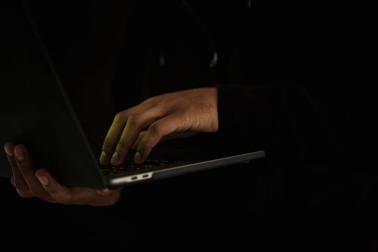 Golpe do WhatsApp clonado: como agir e quem responde pelo prejuízo 5 Crop anonymous male wearing black hoodie working on modern netbook while standing in dark