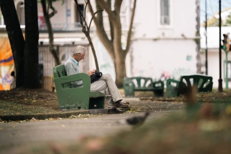 An elderly man sits quietly on a park bench in San José, Costa Rica, enjoying a peaceful d
