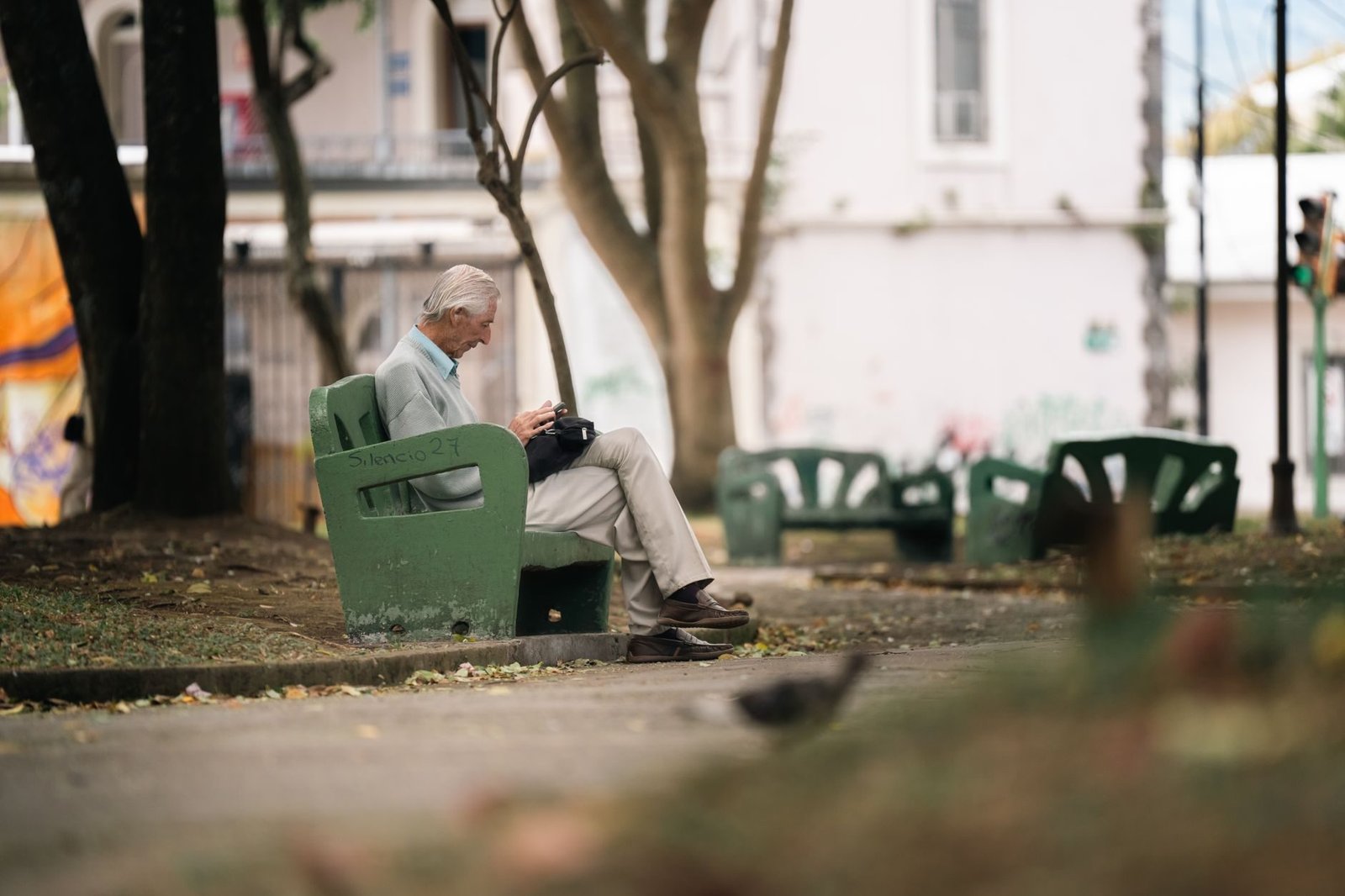 An elderly man sits quietly on a park bench in San José, Costa Rica, enjoying a peaceful d