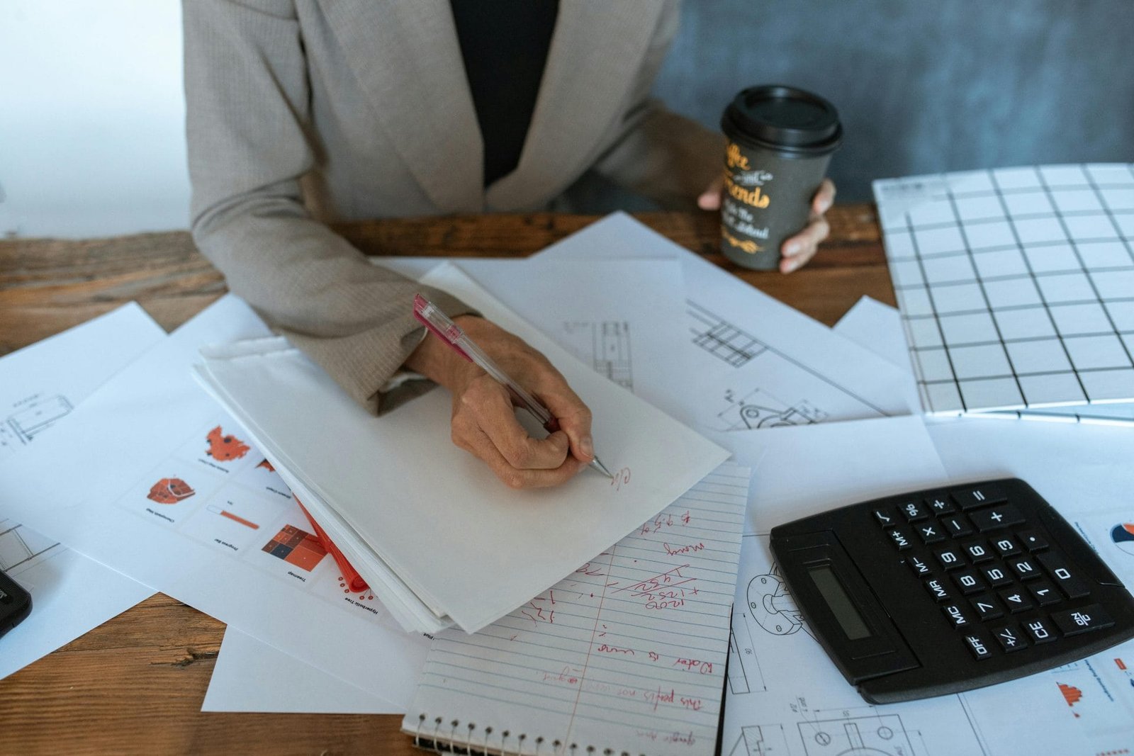Honorários Advocatícios Previdenciários 2026: Quanto Custa? 1 Close-up of a person writing at an office desk with documents and coffee, symbolizing productivity.