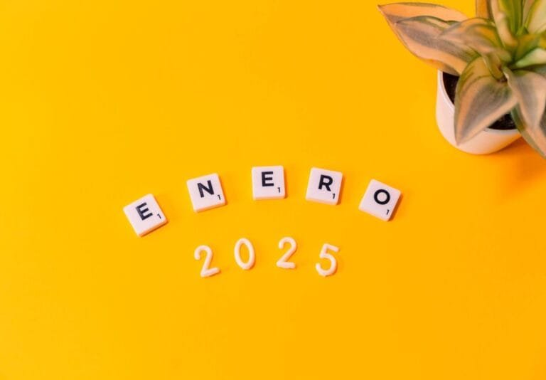 Scrabble tiles spelling Enero 2025 on a vibrant yellow background with a plant