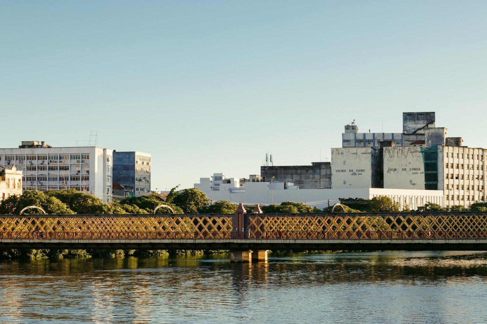 Serene view of a heritage bridge and urban skyline reflecting in calm waters dur