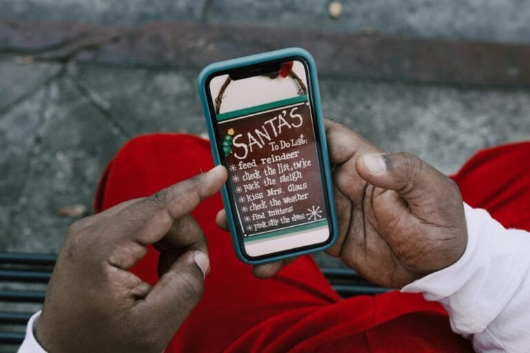Close-up of hands holding a smartphone displaying Santas whimsical to-do list o