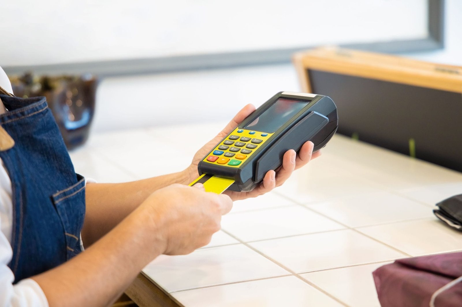 IBS e CBS: Novos Tributos sobre Consumo no Brasil 1 Close-up of hands operating a credit card POS machine in a commercial setting.