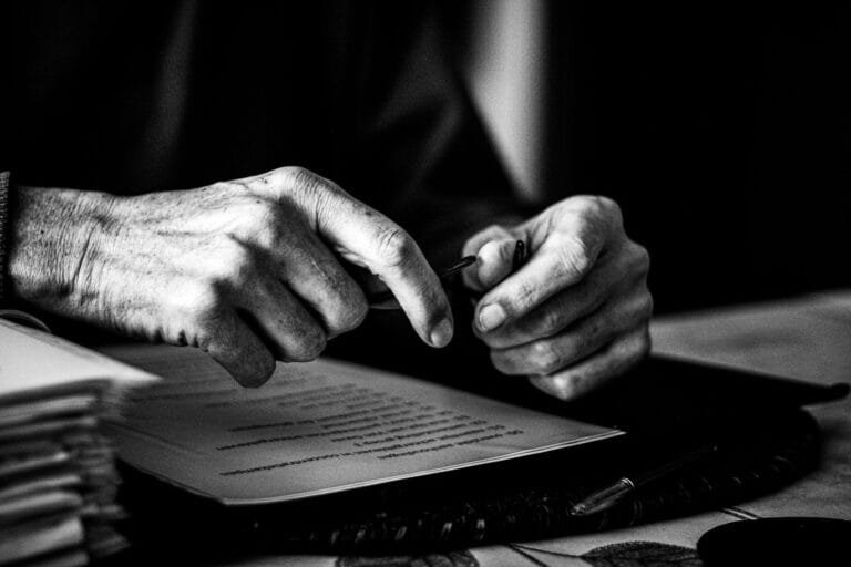 a black and white photo of a persons hands on a book