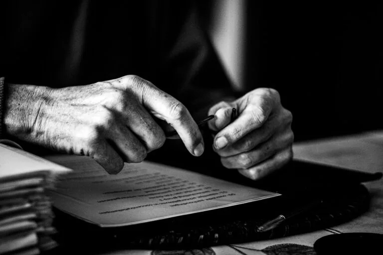 a black and white photo of a persons hands on a book
