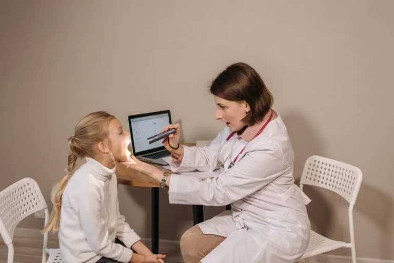 A female doctor examines a child in a clinic setting, ensuring proper medical care and attention.