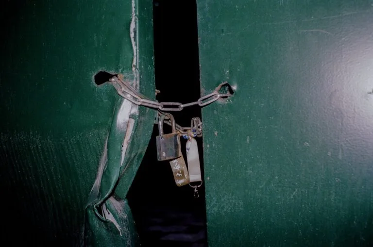 Interdição e fechamento de estabelecimento pela fiscalização: direitos do empresário 6 Close-up of a rusty padlock and chain securing green metal doors, blocking entry.