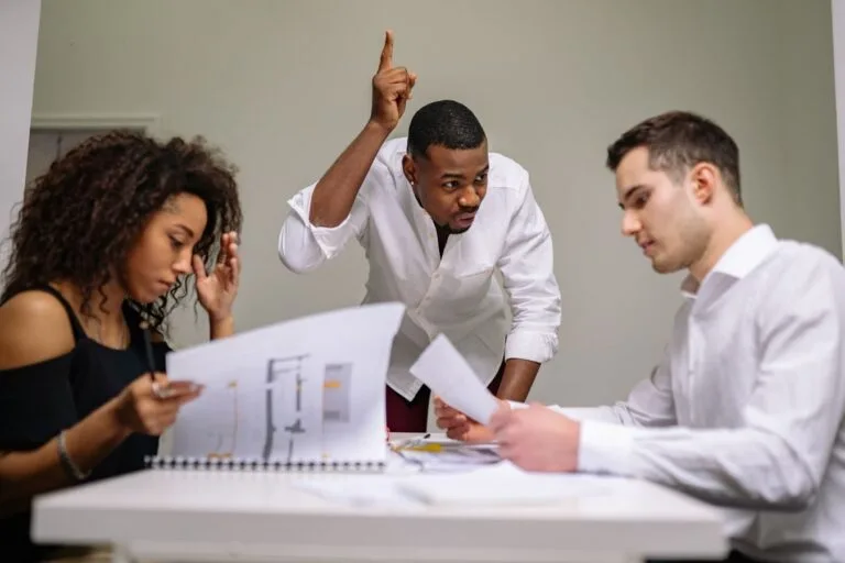 Business professionals engaged in intense discussion over documents in a meeting room.