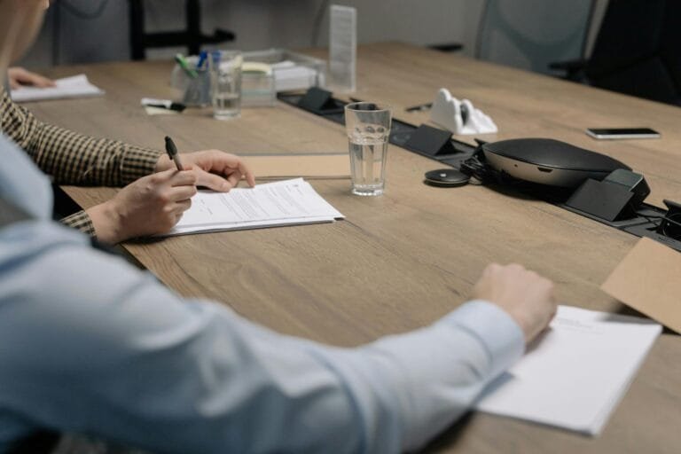 Investidor-Anjo e Contratos de Participação 5 Professional setting of a business meeting with individuals signing documents on a conference table.