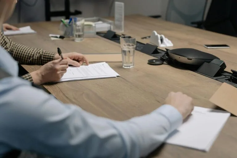 Investidor-Anjo e Contratos de Participação 3 Professional setting of a business meeting with individuals signing documents on a conference table.