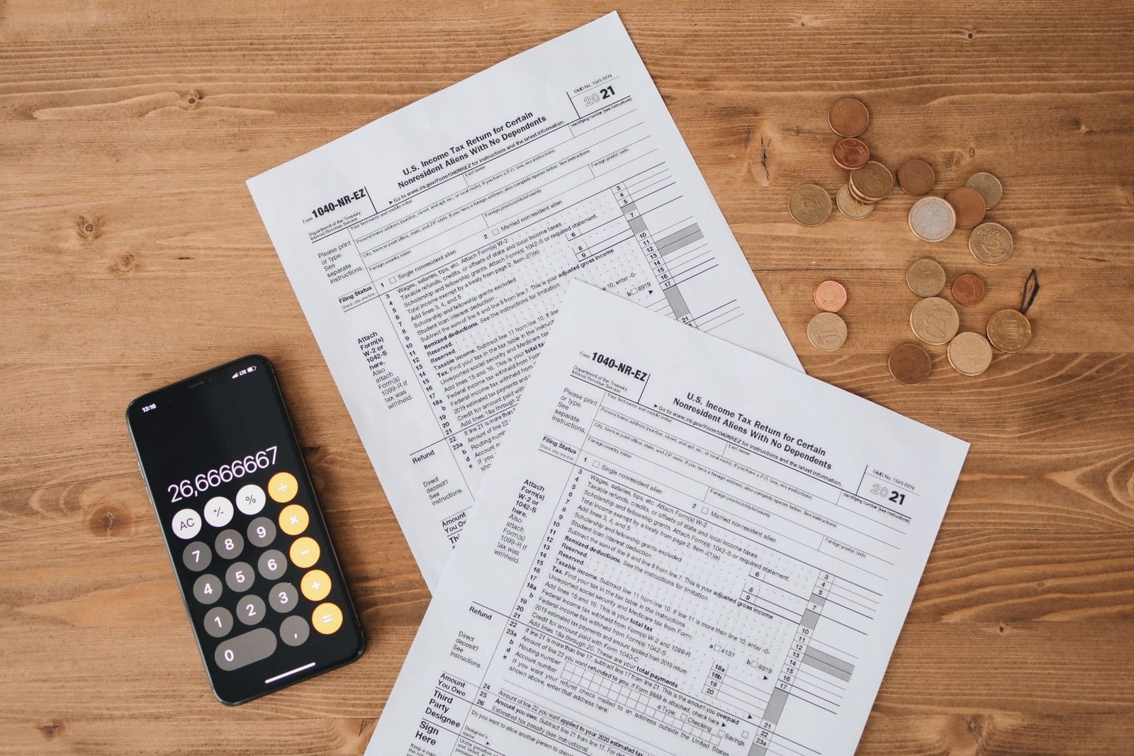 Malha Fina do IRPF: Motivos e Como Resolver 1 Top view of tax documents, calculator, and coins on wooden table.