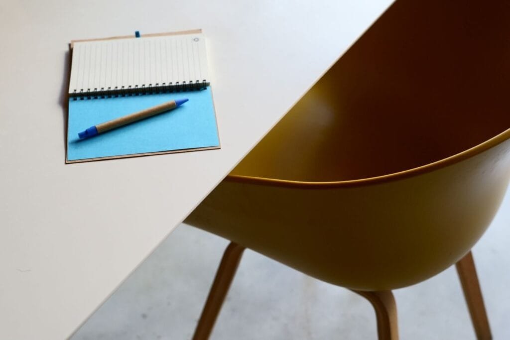 Sou MEI e contribuo. Tenho os mesmos direitos no INSS? 1 Minimalist workspace featuring a table, notebook, and modern yellow chair.