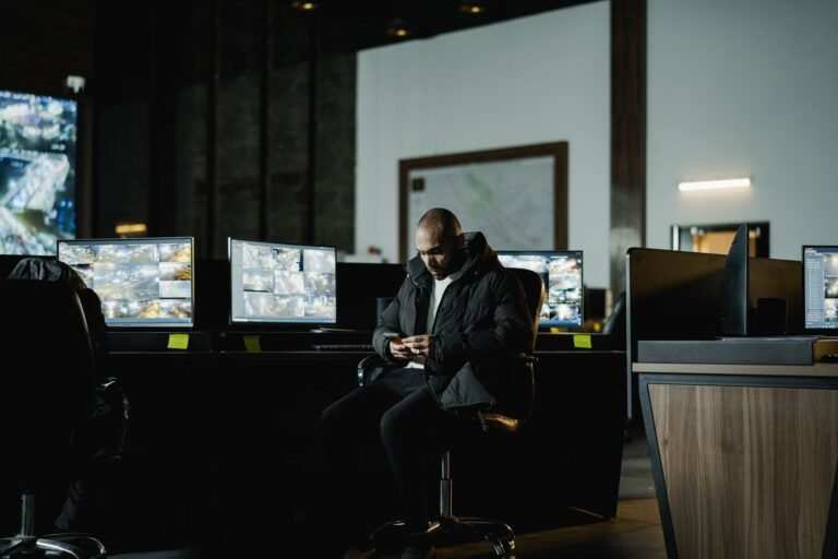 Security officer seated in a dimly lit control room, analyzing multiple surveillance scree