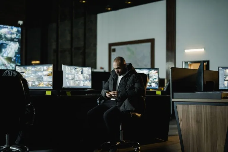 Security officer seated in a dimly lit control room, analyzing multiple surveillance scree