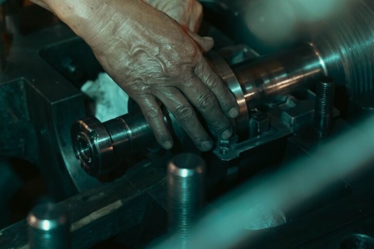 Detailed view of a mechanics hand adjusting parts on a metalworking machine.