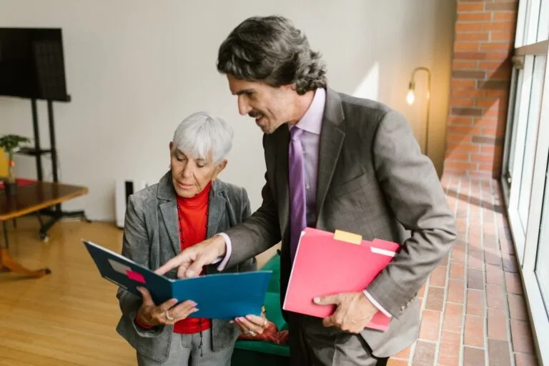 A senior businesswoman and businessman discussing documents in a modern office with natura