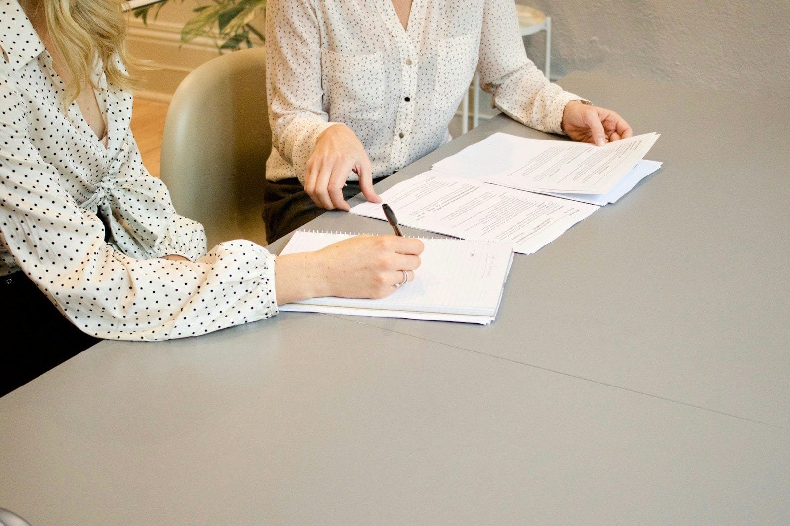 Pensão Especial do Zika: Como Solicitar o Benefício 1 woman signing on white printer paper beside woman about to touch the documents