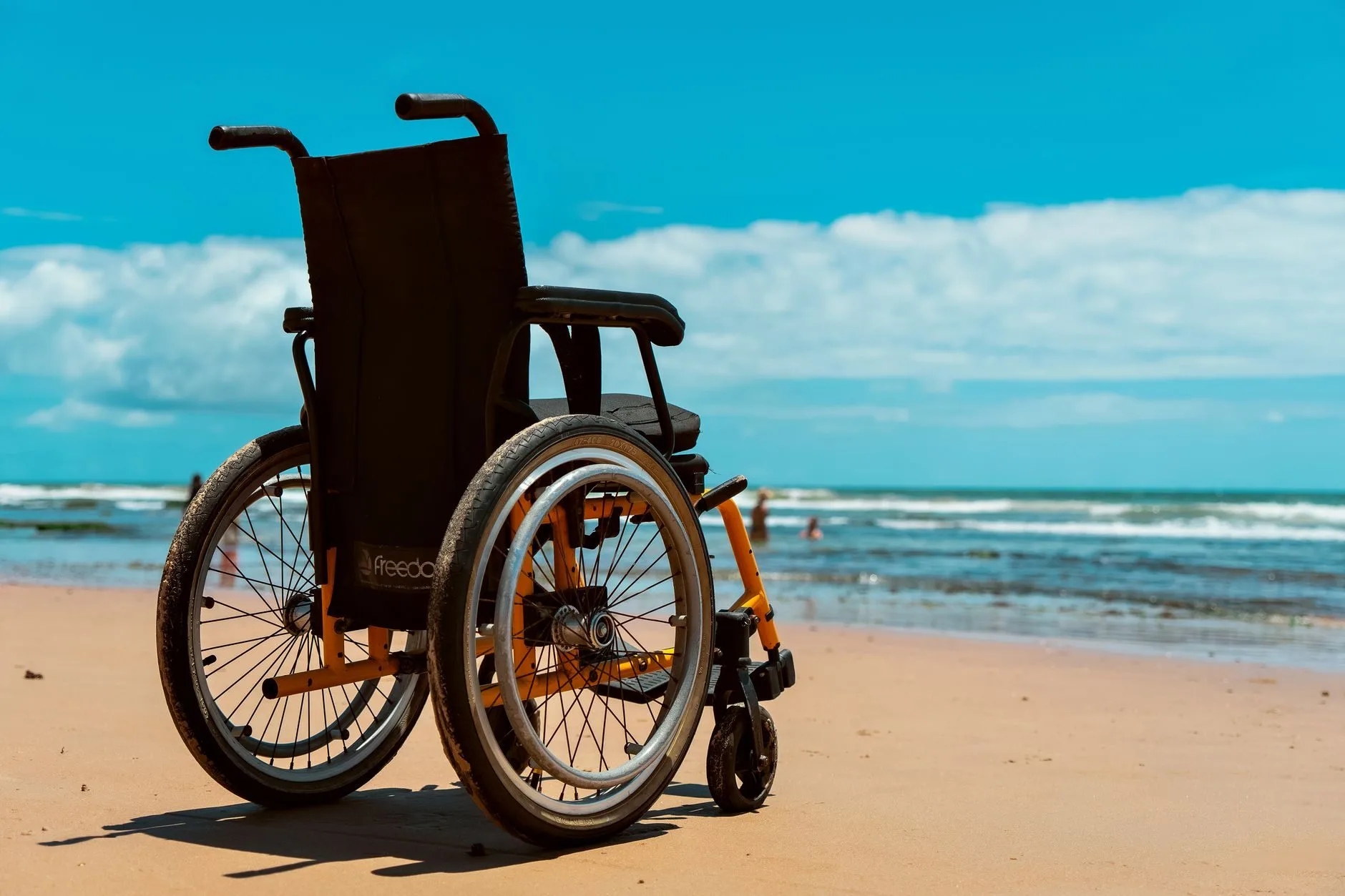 Pensão por morte e o dependente inválido ou com deficiência 1 A wheelchair on a sandy beach overlooking the sea on a bright summer day.