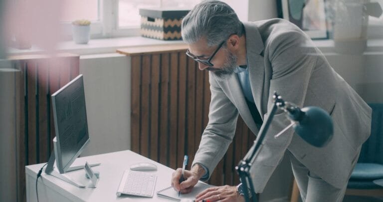 A man in a suit writing on a piece of paper
