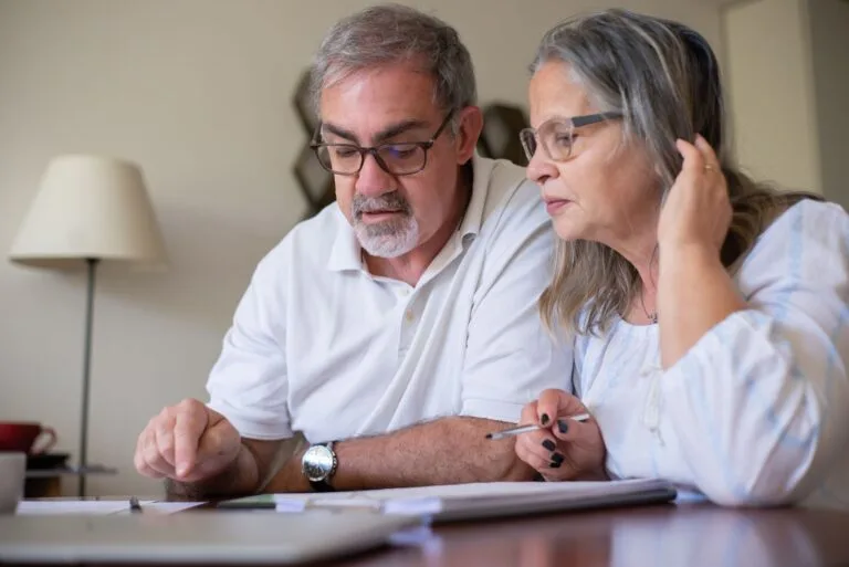 Planejamento previdenciário: por que organizar a aposentadoria com antecedência 2 Elderly couple enjoying leisure time with crosswords at home, showcasing togetherness.