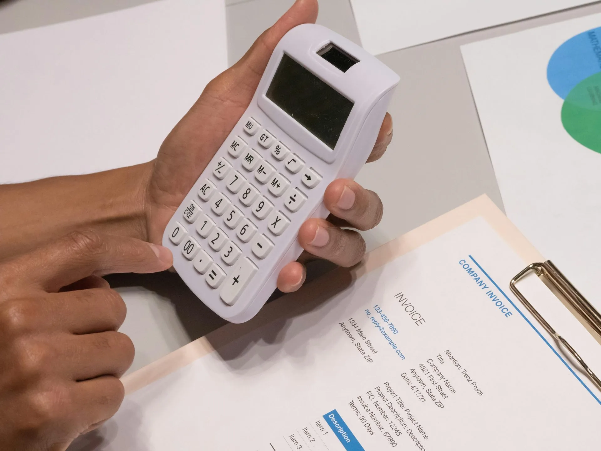 Planejamento Tributário Lícito: Elisão vs. Evasão Fiscal 1 Close-up of hands using a calculator next to a company invoice, depicting a financial calculation concept.