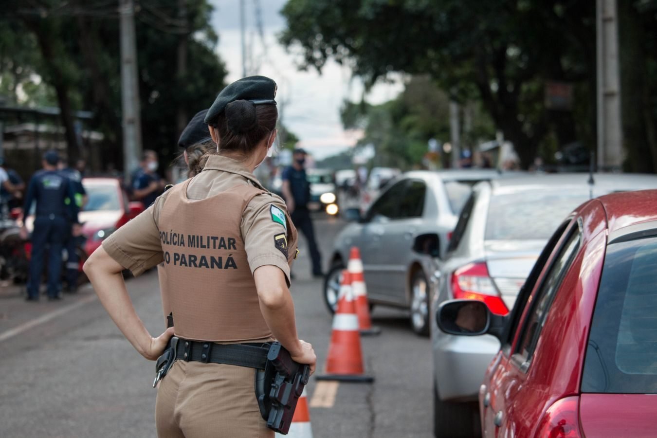 Poder de policia: ate onde o Estado pode limitar a atividade do particular 1 Back view of a police officer in uniform controlling traffic on a busy road.