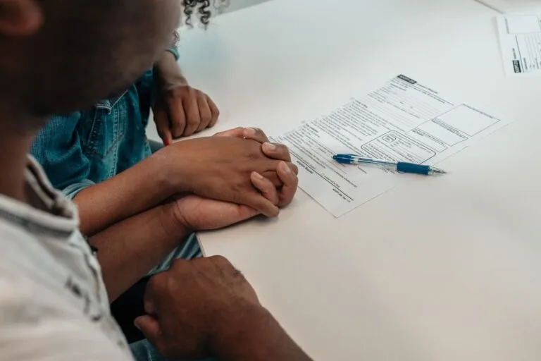 A family supports each other during an adoption process, holding hands over important docu