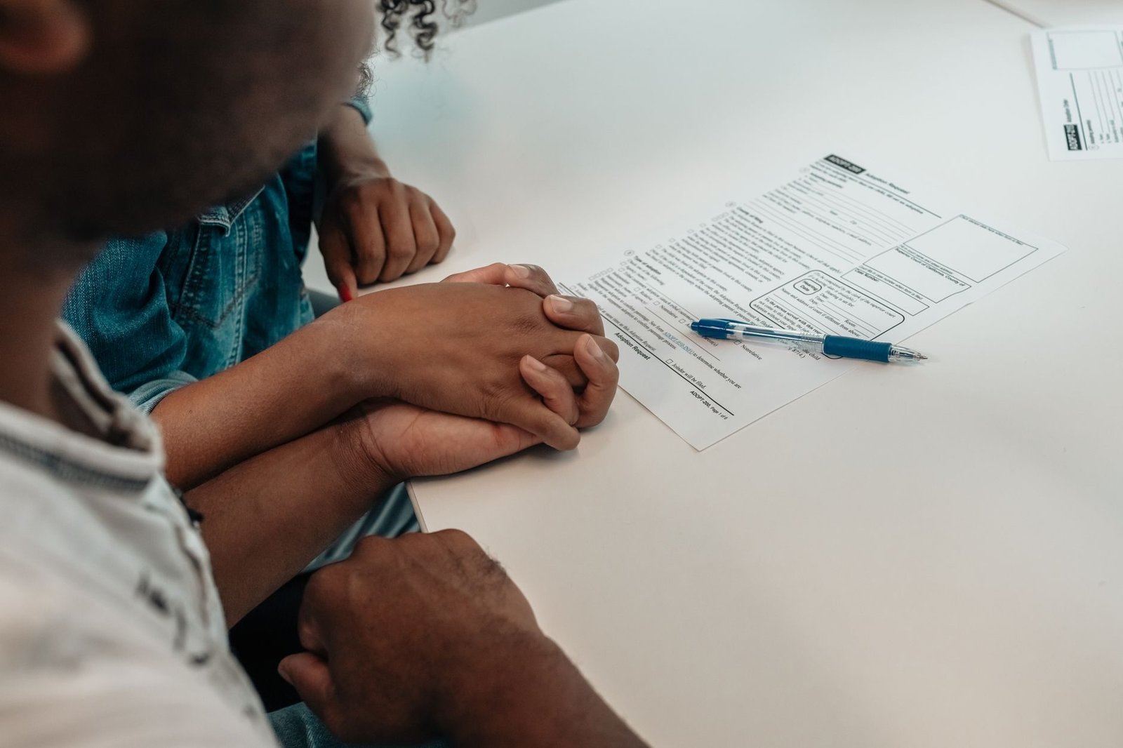 A family supports each other during an adoption process, holding hands over important docu