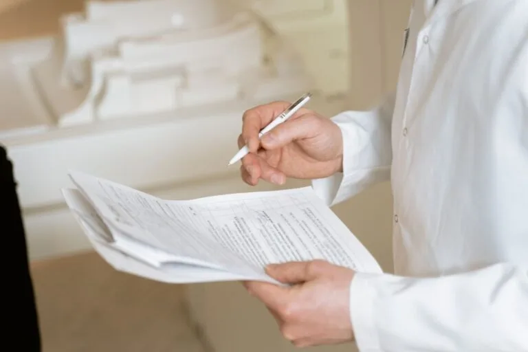Portaria Conjunta MPS/INSS nº 83/2025 amplia para até 60 dias, com vigência de 120 dias, o auxílio por incapacidade concedido por análise documental 6 A doctor holds and reviews medical documents, demonstrating careful examination and professionalism.