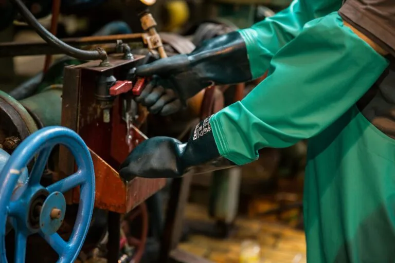PPP: O Que É, Quem Emite e Como Solicitar ao Empregador 6 Industrial worker in protective gear handling a valve in a factory setting, ensuring safety and precision.