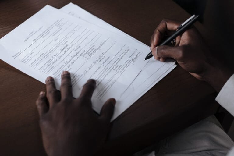 Prescrição e Decadência no INSS: Prazos Importantes 2026 1 A detailed view of a man signing official documents with a pen at a table.