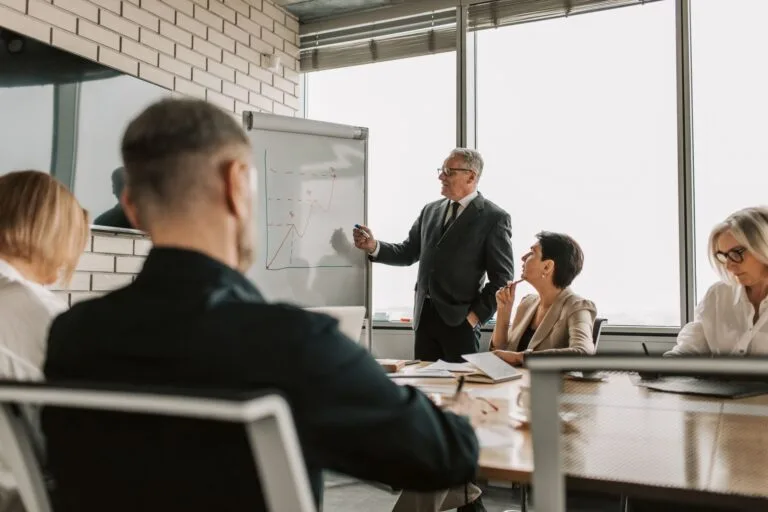 Senior leader presenting growth charts in a business meeting with colleagues in a modern o