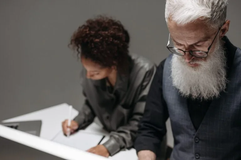 Two professionals working collaboratively at a desk in an office environment.