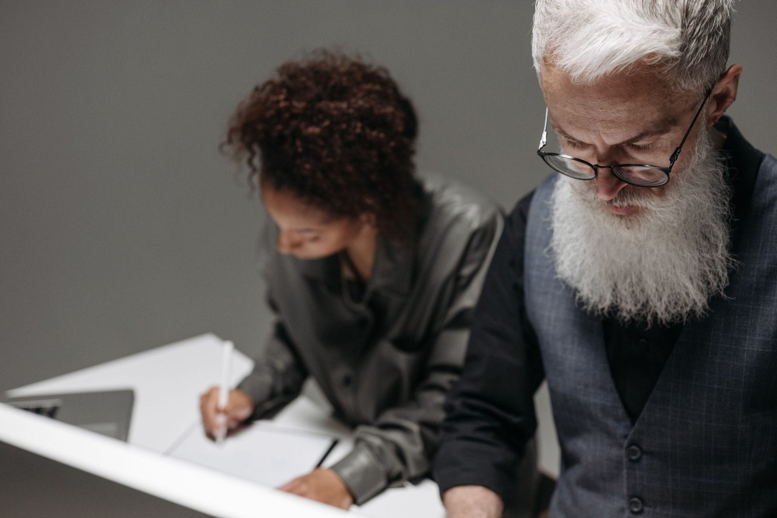 Two professionals working collaboratively at a desk in an office environment.
