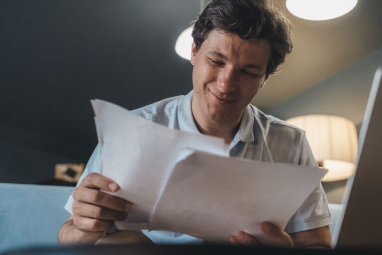 A cheerful man reading papers in a cozy indoor setting, radiating positivity.