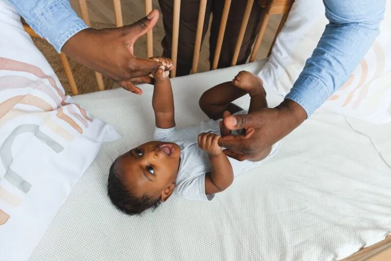 A tender moment showing a father lovingly holding his baby's hand while the baby lies in a