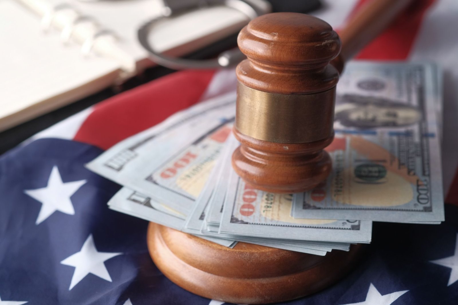 Close-up of a judge's gavel resting on US dollar bills and an American flag, symbolizing j