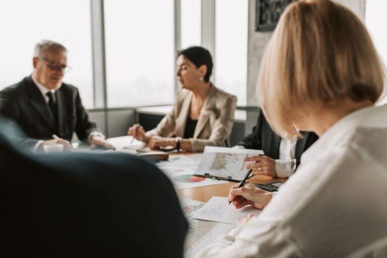 Colleagues discussing documents in a corporate office meeting.