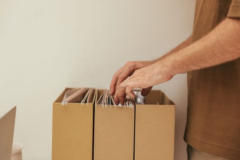 Recurso administrativo no INSS: como contestar o indeferimento sem ir ao Judiciário 7 Close-up of a person organizing files in cardboard boxes, ideal for business and office themes.